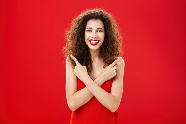 Donna soddisfatta di qualsiasi decisione sentendosi spensierata e felice in piedi in un elegante abito da sera rosso con...