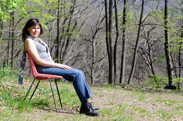 Donna sola seduta su una sedia e rilassante in un parco