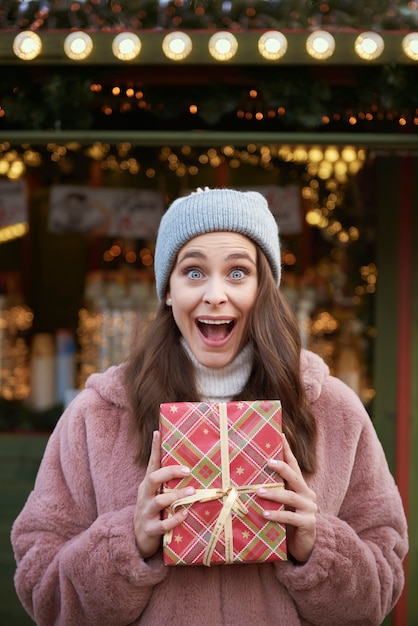 Donna sorpresa con regali di Natale sul mercatino di Natale