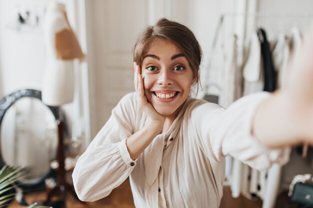 Donna sorpresa in camicia bianca che prende selfie