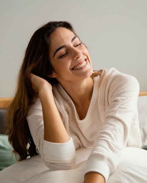 Donna sorridente a letto a casa