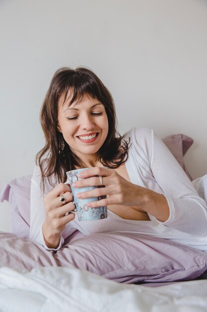 Donna sorridente a letto con caffè