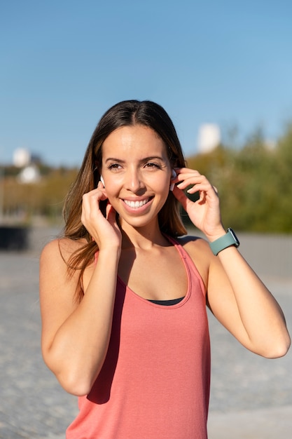 Donna sorridente a tiro medio con gli auricolari