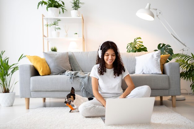 Donna sorridente a tutto campo sul pavimento con il laptop