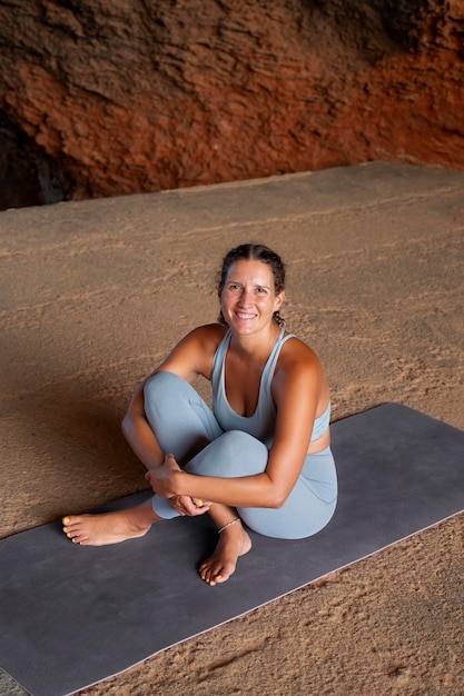 Donna sorridente a tutto campo sul tappetino da yoga
