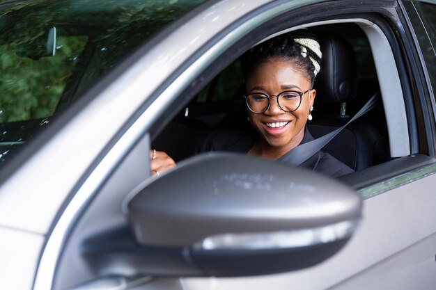 Donna sorridente alla guida della sua auto personale