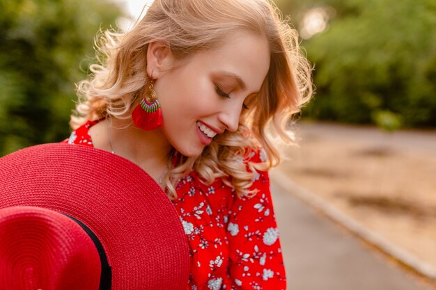 Donna sorridente bionda elegante attraente in cappello rosso di paglia e vestito di moda estiva camicetta