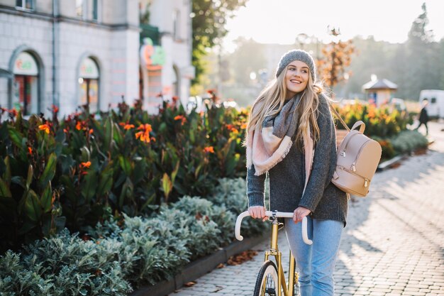 Donna sorridente che cammina con la bicicletta nel parco