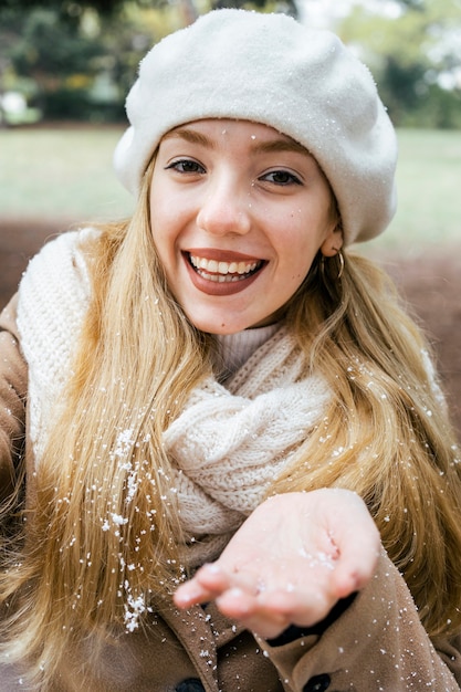 Donna sorridente che cattura selfie nel parco durante l'inverno con la neve