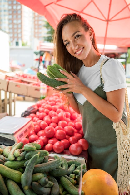 Donna sorridente che cattura un mazzo di cetrioli