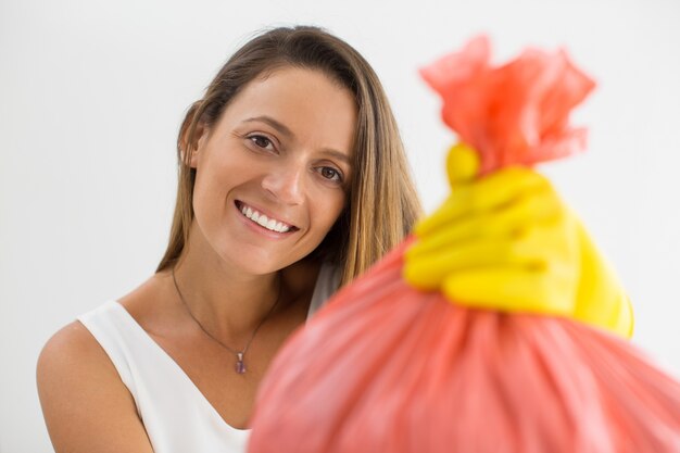 Donna sorridente che dà pieno sacchetto di spazzatura