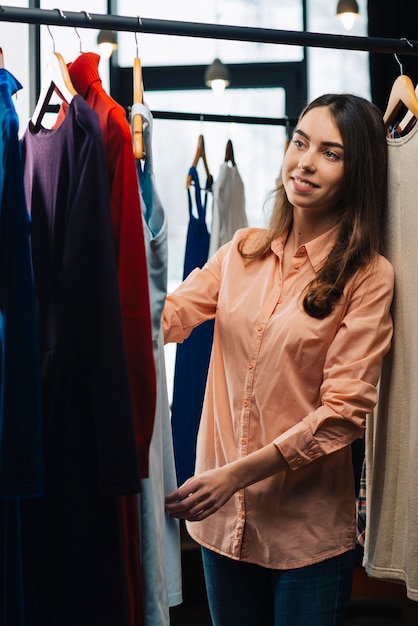 Donna sorridente che esamina i vestiti sullo scaffale dei vestiti