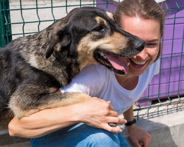 Donna sorridente che gioca con il cane in adozione