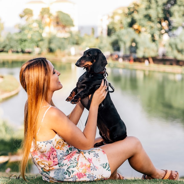 Donna sorridente che gioca con il suo cane vicino al lago