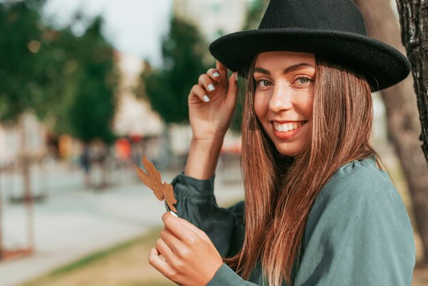 Donna sorridente che indossa un cappello nero con copia spazio