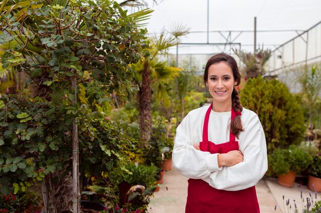 Donna sorridente che indossa vestiti di giardinaggio in serra