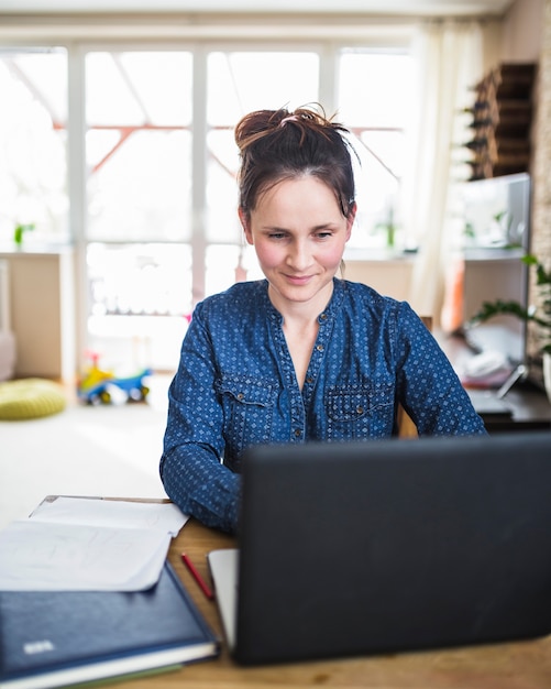 Donna sorridente che lavora al computer portatile a casa