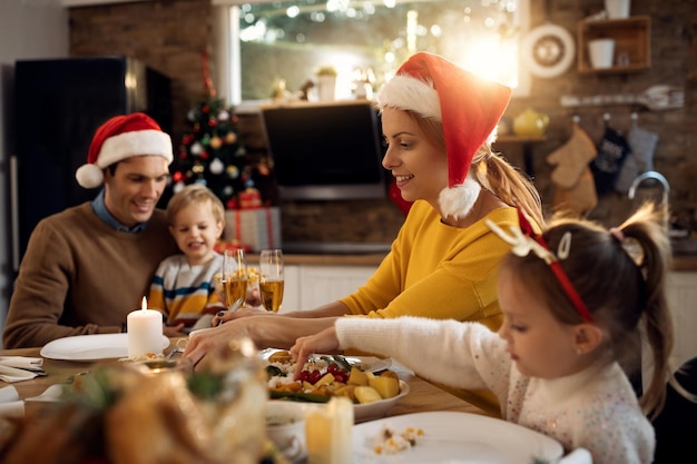 Donna sorridente che mangia il pranzo di Natale con la sua famiglia nella sala da pranzo