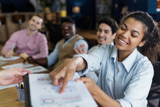 Donna sorridente che mostra grafico in ufficio con i colleghi