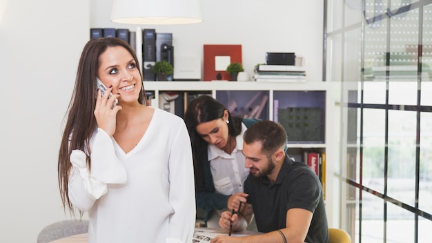 Donna sorridente che parla sul telefono in ufficio