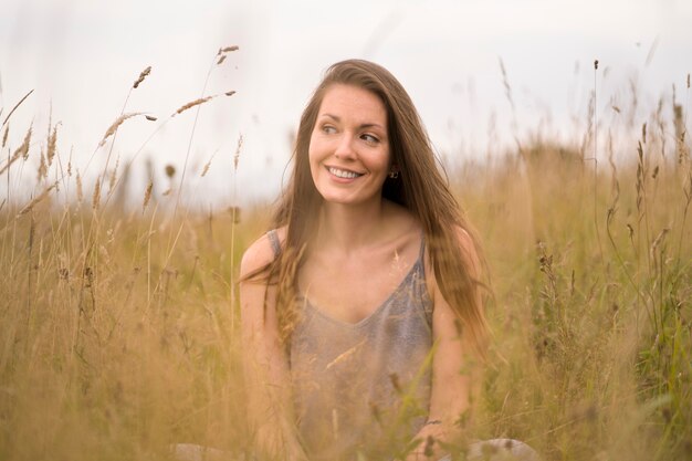 Donna sorridente che posa nel colpo medio della natura