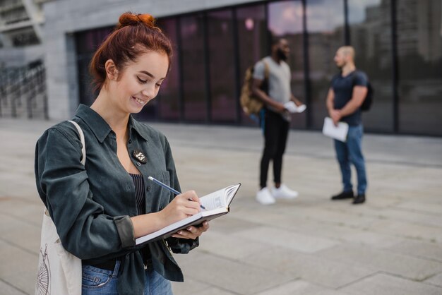 Donna sorridente che scrive nel blocchetto per appunti