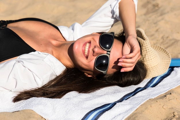 Donna sorridente che si abbronza sulla spiaggia