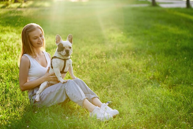 Donna sorridente che tiene bulldog francese sull'erba