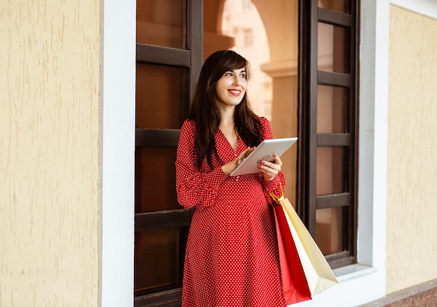 Donna sorridente che tiene i sacchetti della spesa e tablet