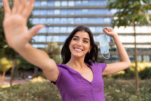 Donna sorridente che tiene la maschera per il viso vista frontale