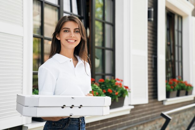 Donna sorridente che tiene scatole di pizza