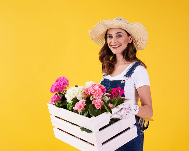 Donna sorridente che tiene una cassa di legno con fiori