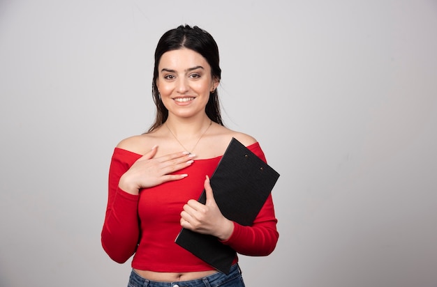 Donna sorridente che tiene una lavagna per appunti e che esamina la macchina fotografica.