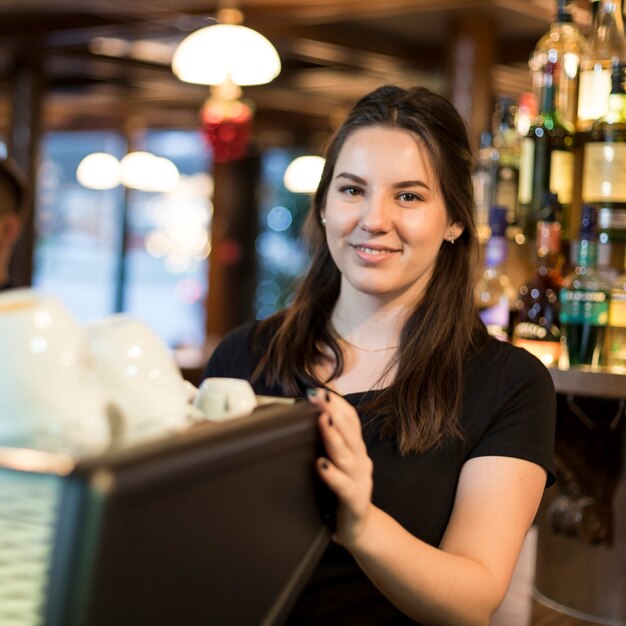 Donna sorridente che usando la macchina del caffè