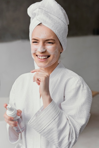 Donna sorridente che utilizza una crema per il viso bianca