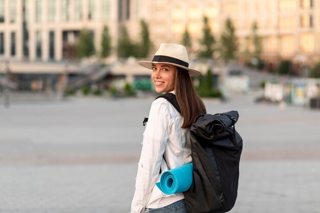 Donna sorridente che viaggia da sola con lo zaino