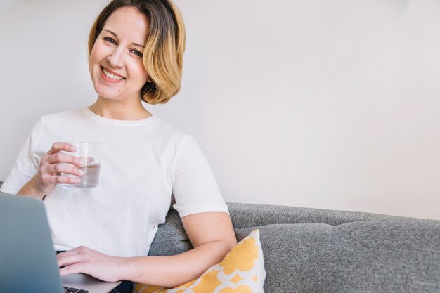 Donna sorridente con acqua e laptop