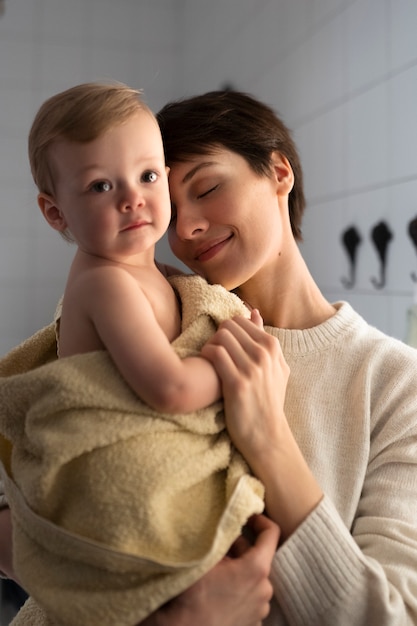 Donna sorridente con colpo medio che tiene bambino