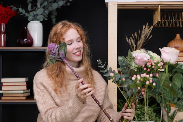 Donna sorridente con colpo medio che tiene fiore