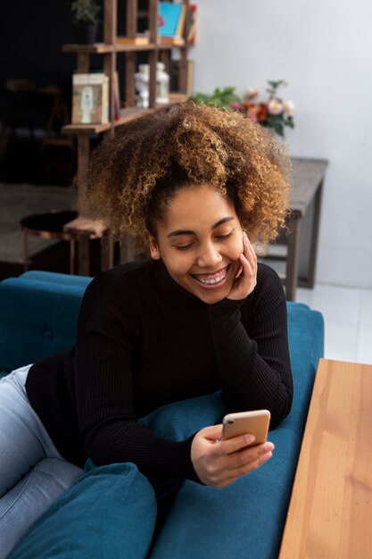 Donna sorridente con colpo medio che tiene il telefono