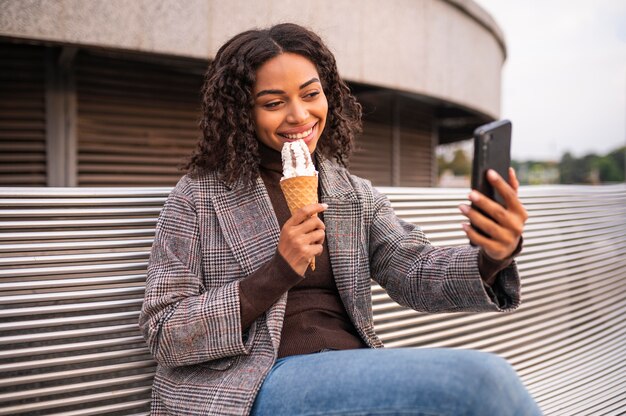 Donna sorridente con gelato all'aperto e prendendo selfie