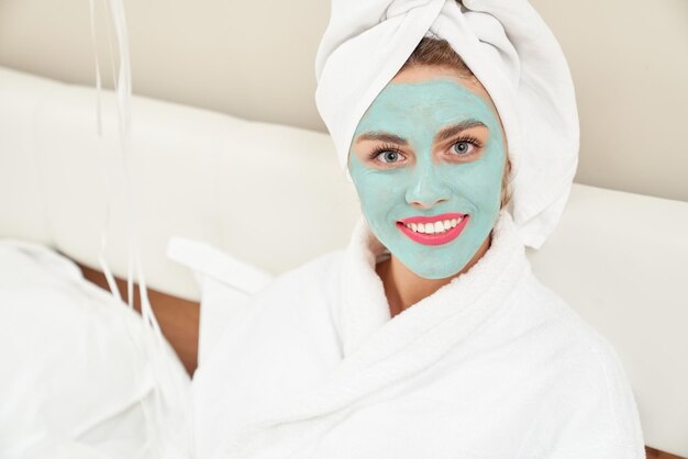 Donna sorridente con maschera cosmetica sul viso