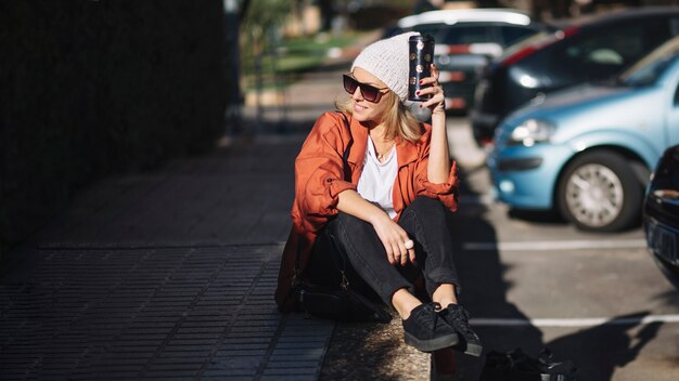 Donna sorridente con thermos sul parcheggio