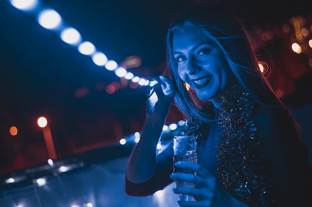 Donna sorridente con un bicchiere di champagne e lampade blu