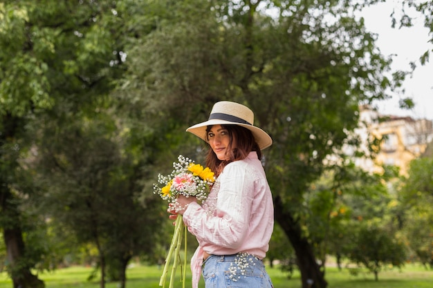 Donna sorridente con un mazzo di fiori nel parco