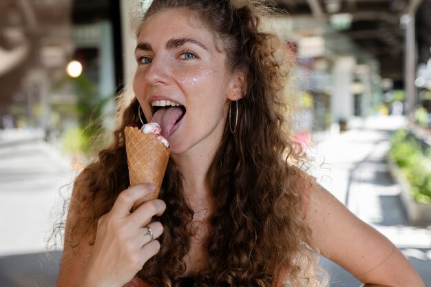 Donna sorridente del colpo medio che lecca il gelato