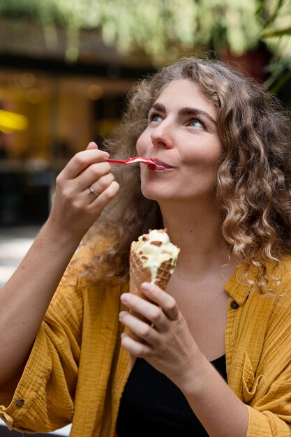 Donna sorridente del colpo medio che mangia il gelato