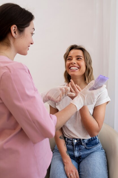 Donna sorridente del colpo medio che ottiene riempitivo per le labbra