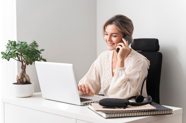 Donna sorridente del colpo medio che parla sul telefono