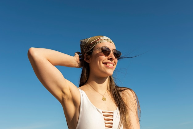 Donna sorridente del colpo medio che posa alla spiaggia?